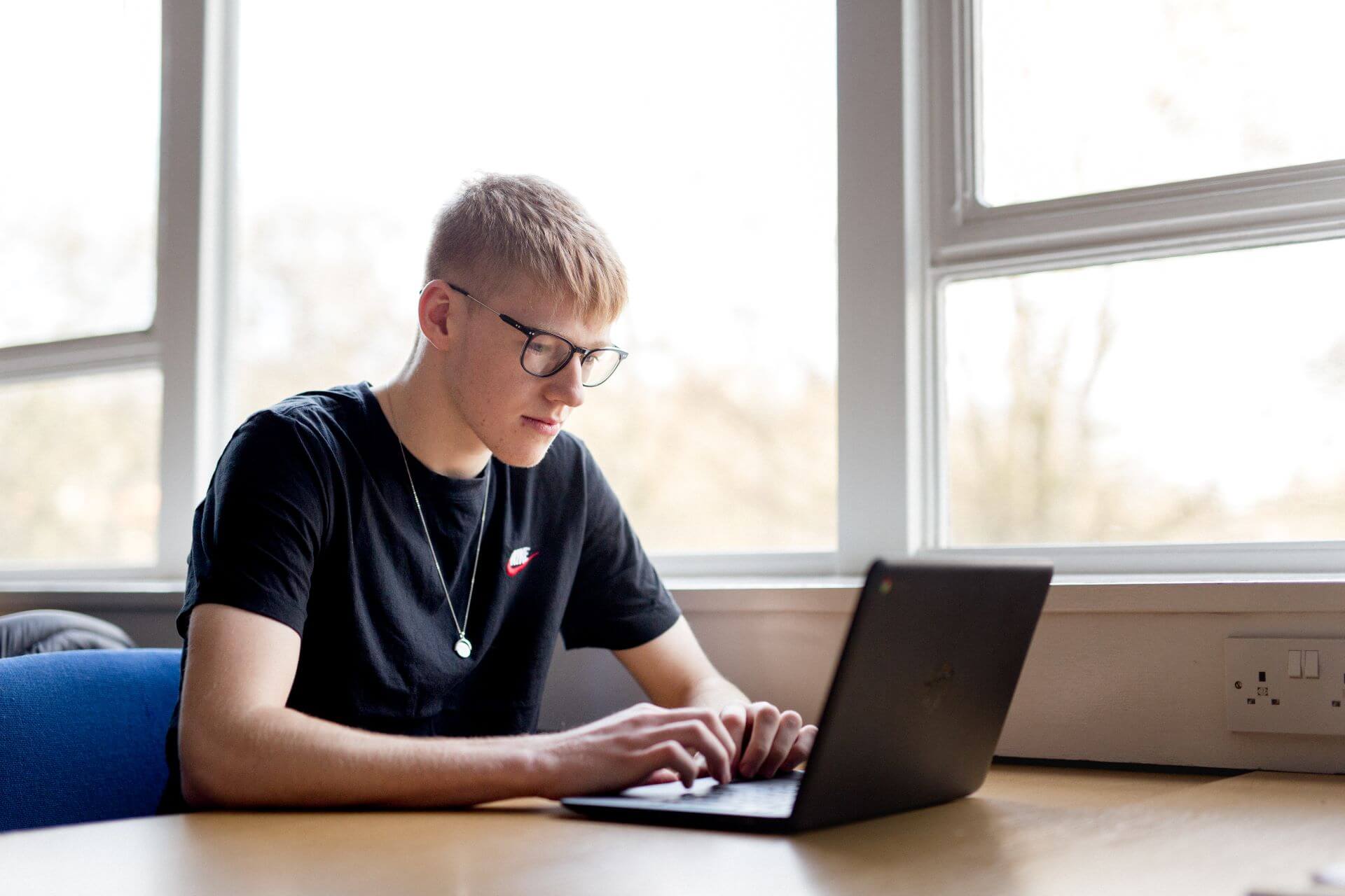 A student at a desk working on his laptop