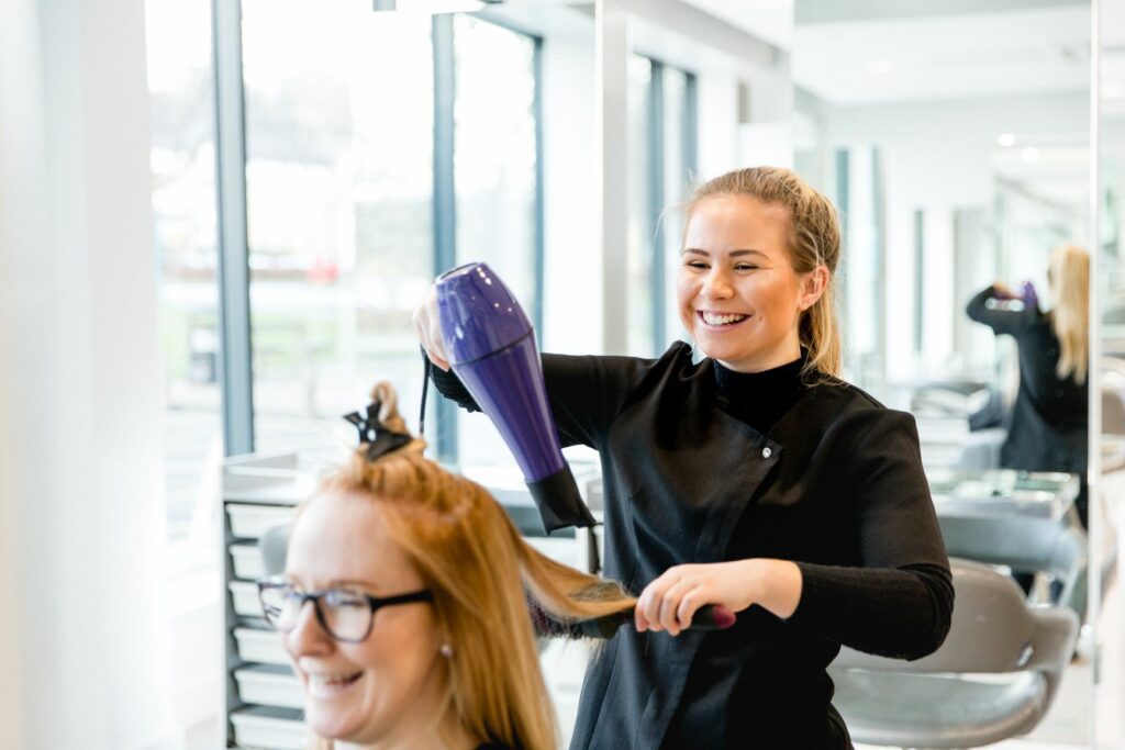 A student blow drying someones hair