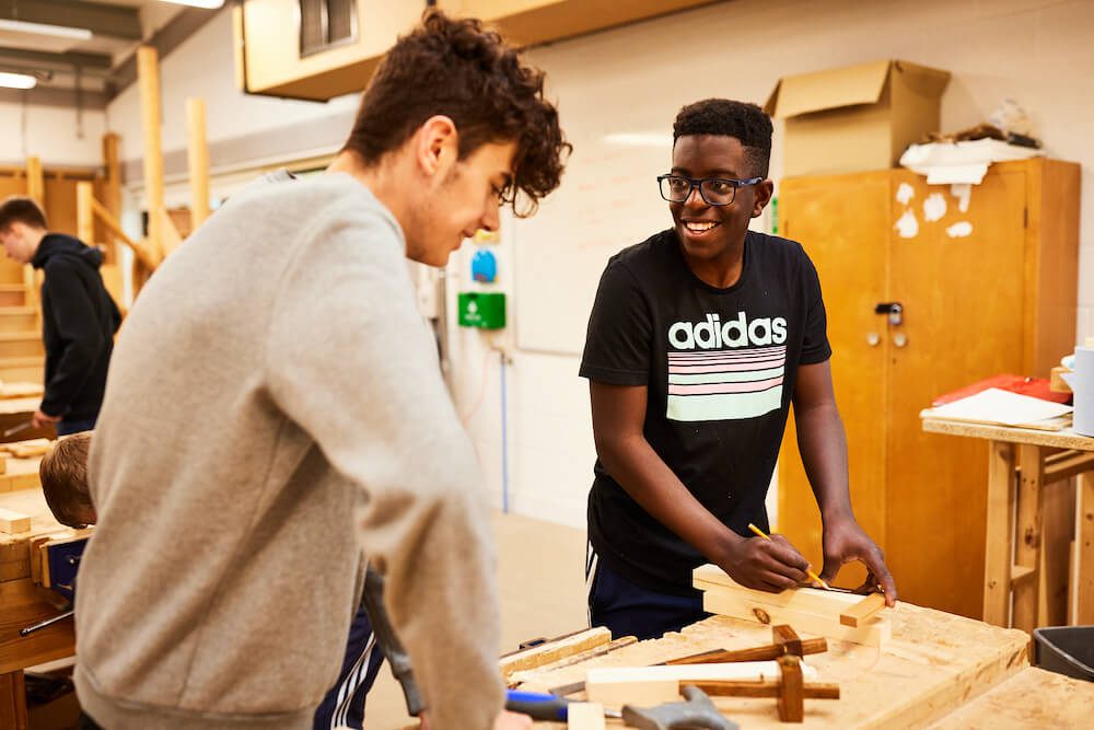 http://Two%20students%20smiling%20doing%20woodwork