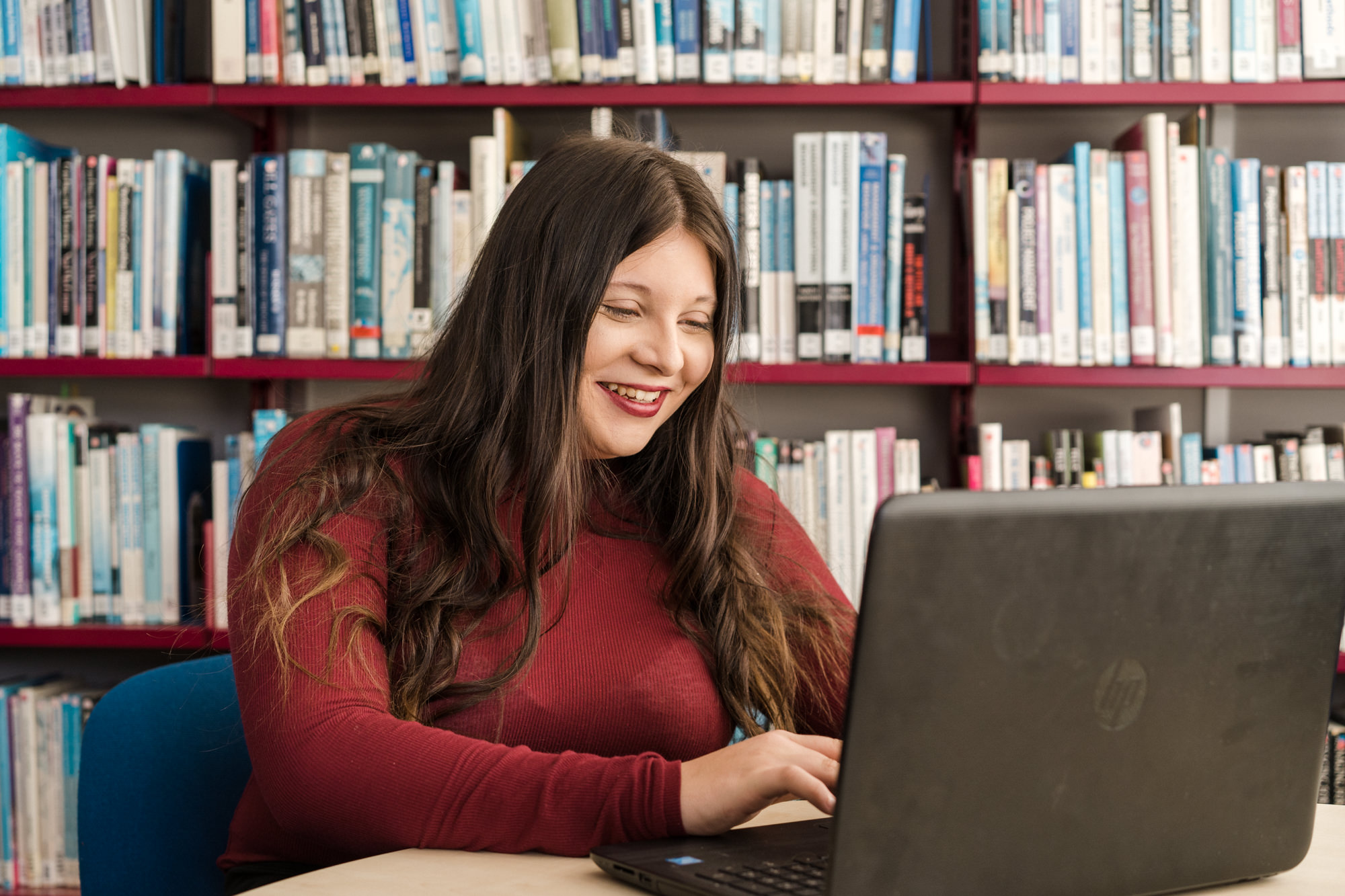Female student sitting in a library working on her laptop