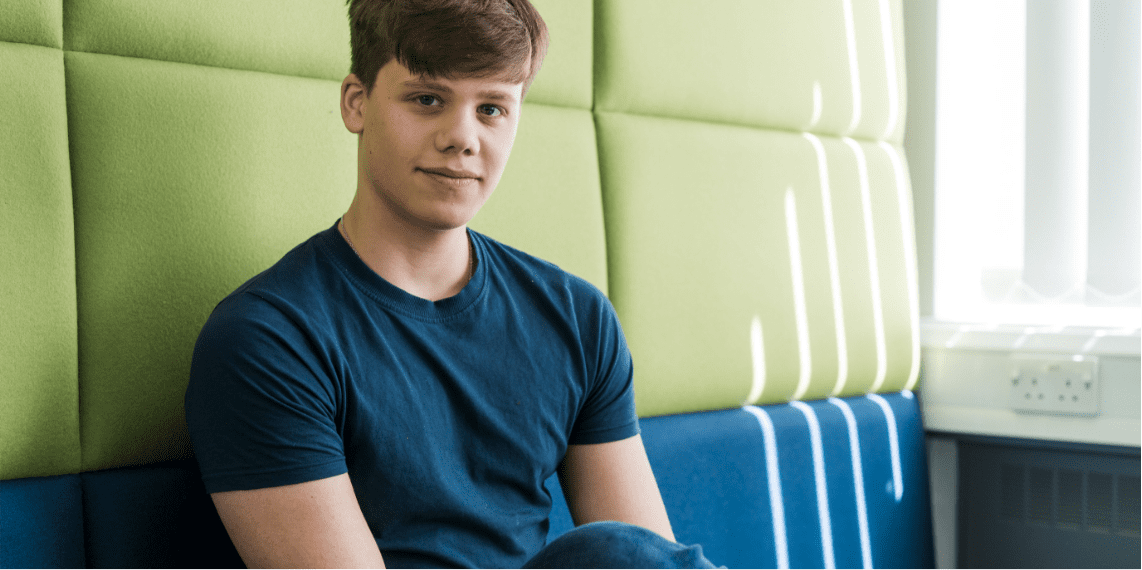 Male student sitting down smiling at the camera