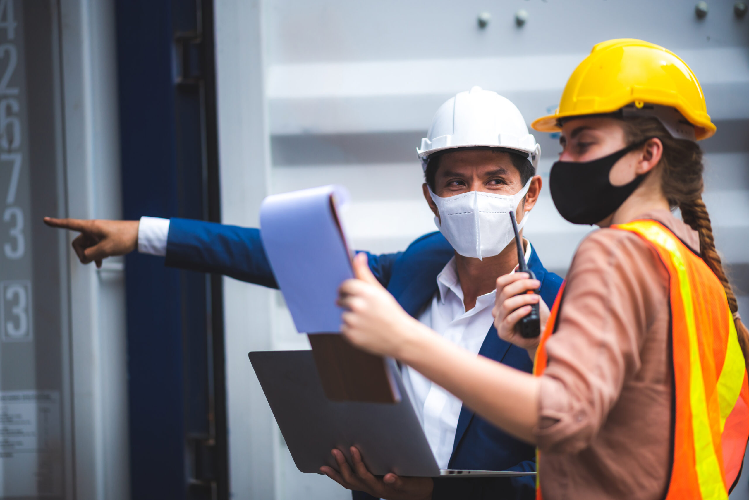 executives businessmen, and engineers or foreman wear medical face masks. Quality Control Officer inspecting warehouses at containers yard for international shipping businesses Concepts of import and export