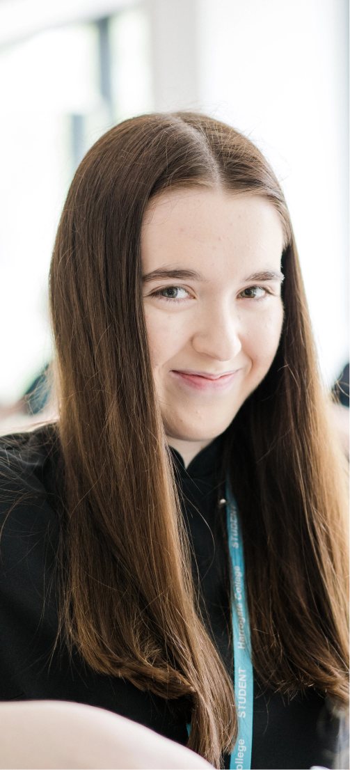 Female student with long hair wearing a Harrogate College lanyard in black top smiling