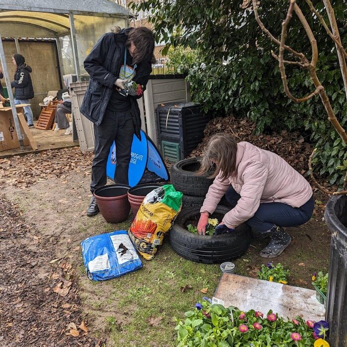 Two people planting flowers outside in the Garden of Sanctuary at Harrogate College