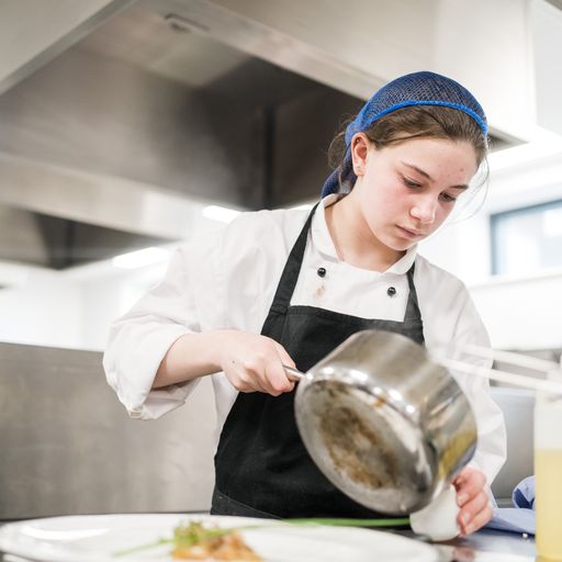 Female Harrogate College culinary student making gravy in the student kitchens