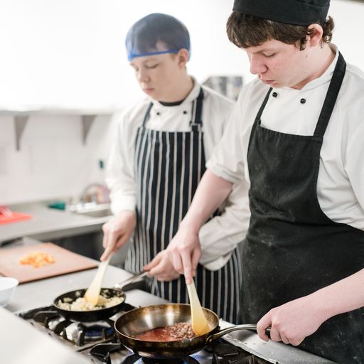 Two male Harrogate College culinary students working in the kitchen creating a main course meal