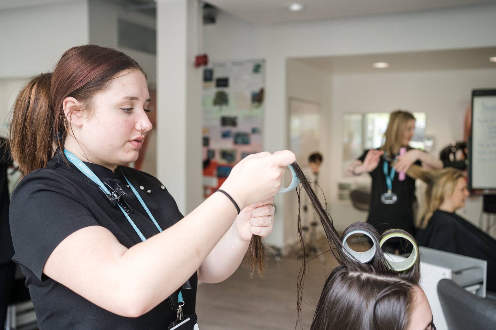 Harrogate College Women's hair dressing student rolling a clients hair