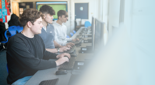 Students sat in a computer room working on desktop computers