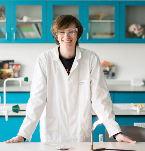 Harrogate College science student wearing lab coat standing smiling in the laboratory