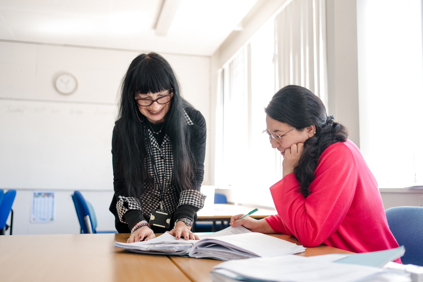 Support worker and adult student having discussion looking at notes smiling