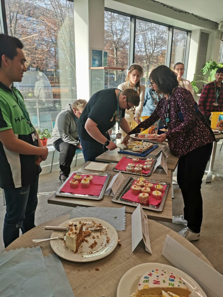 people gathered round a table with cakes on it