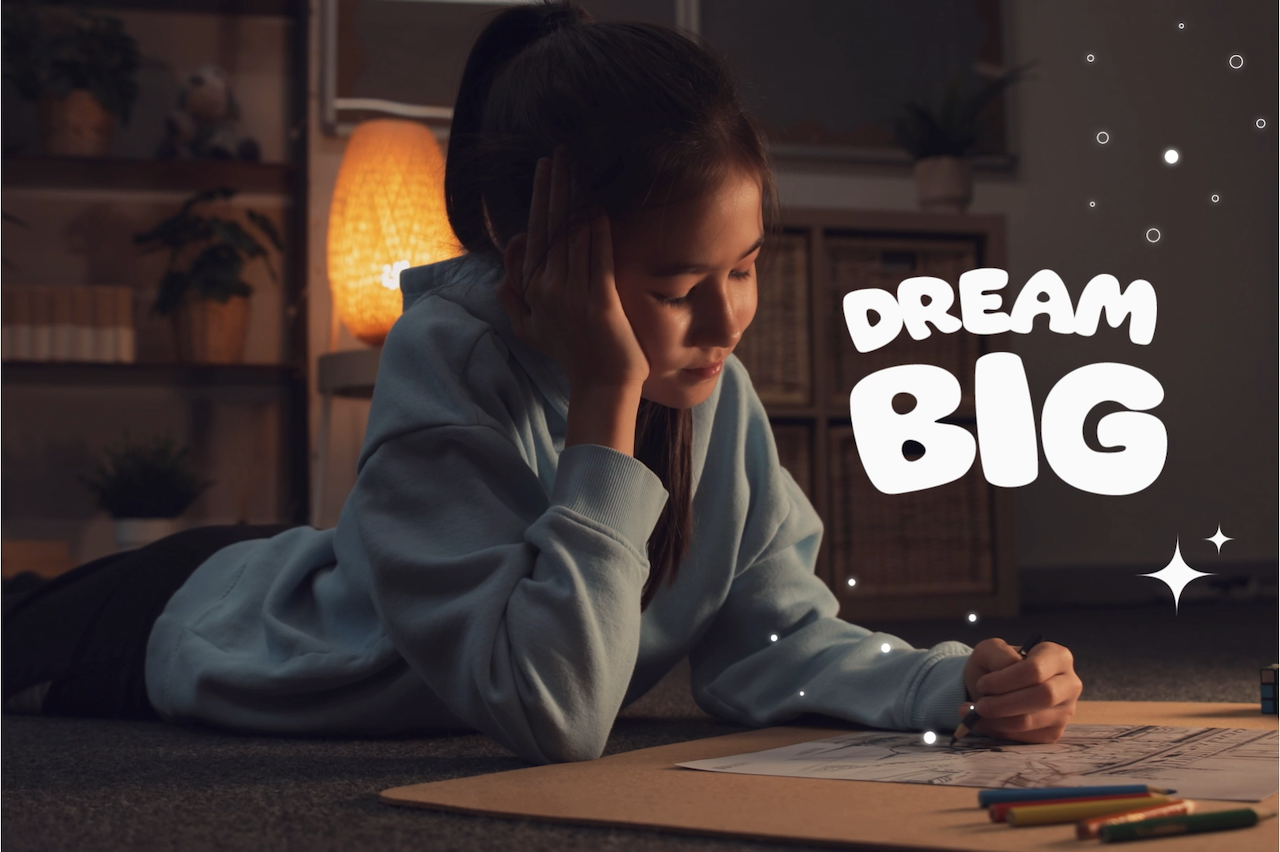 A child coloring on the floor with white text dream big