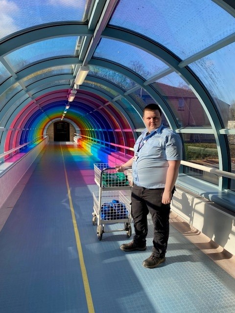 Harrogate student standing in a colourful bridge with a trolley