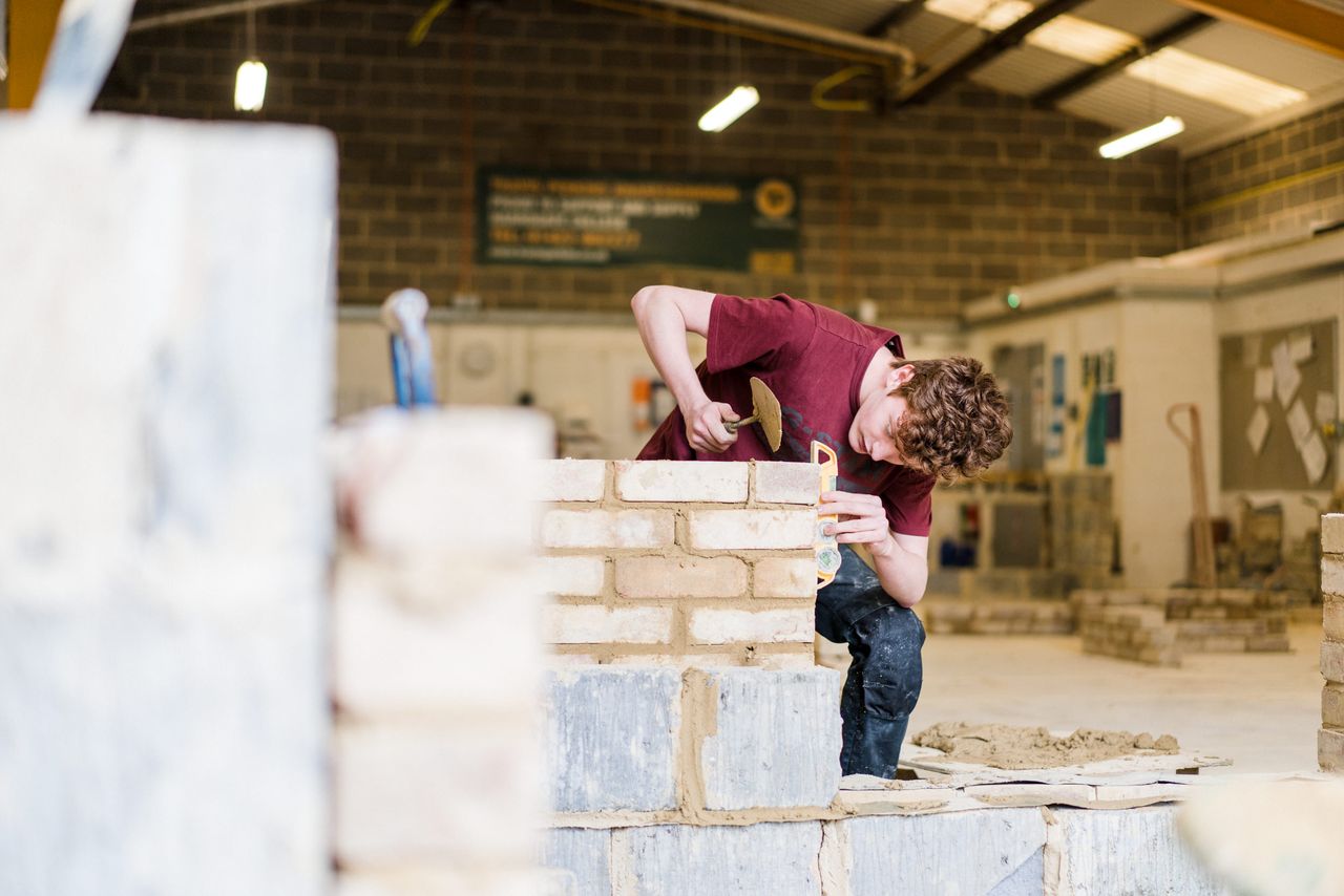 Harrogate College Construction student laying bricks and checking the level