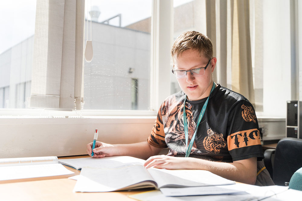 Adult student sat in classroom writing notes in textbooks