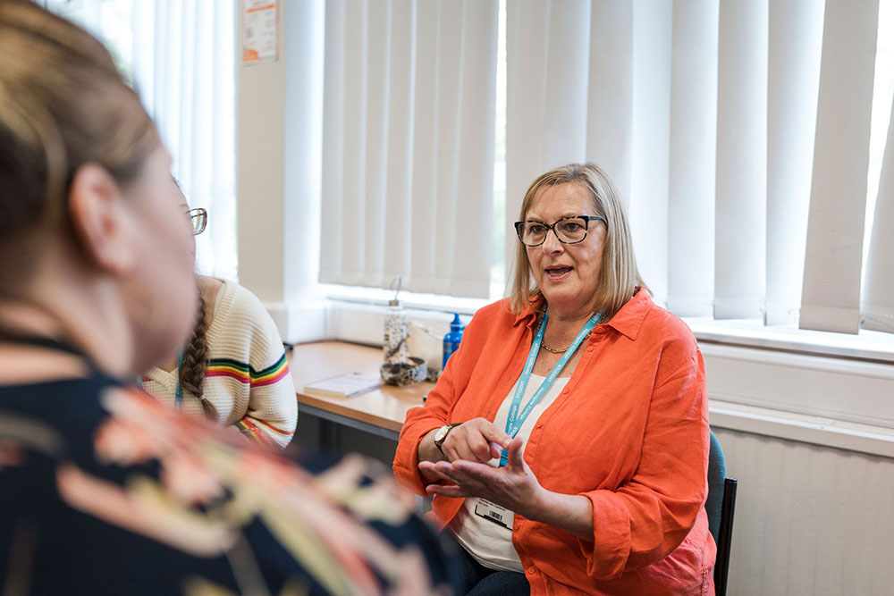 Adult sat in Harrogate College using sign language to communicate
