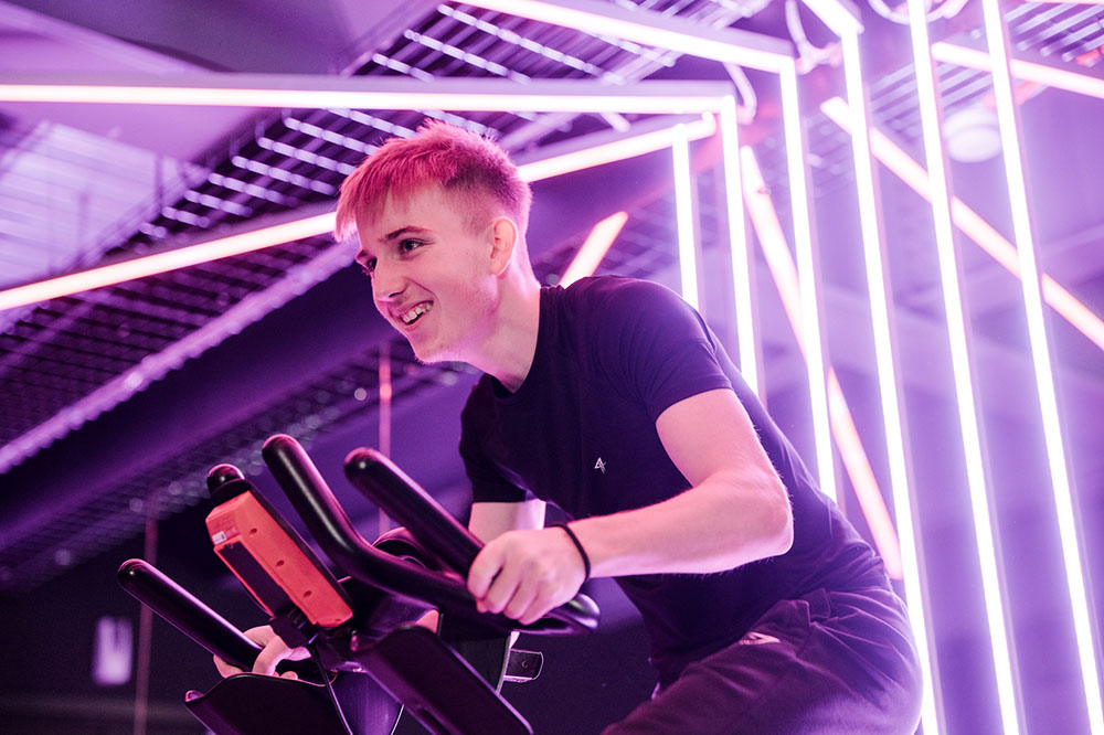 Student sat on an exercise bike with bright lighting in the background