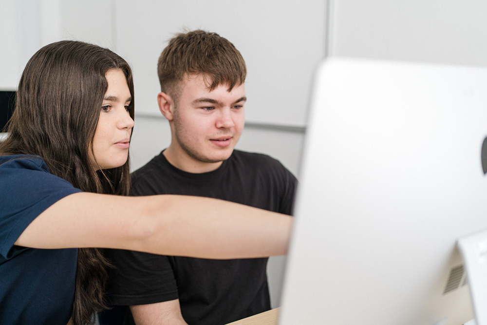 Two Harrogate College students sat together working on a desktop Mac computer