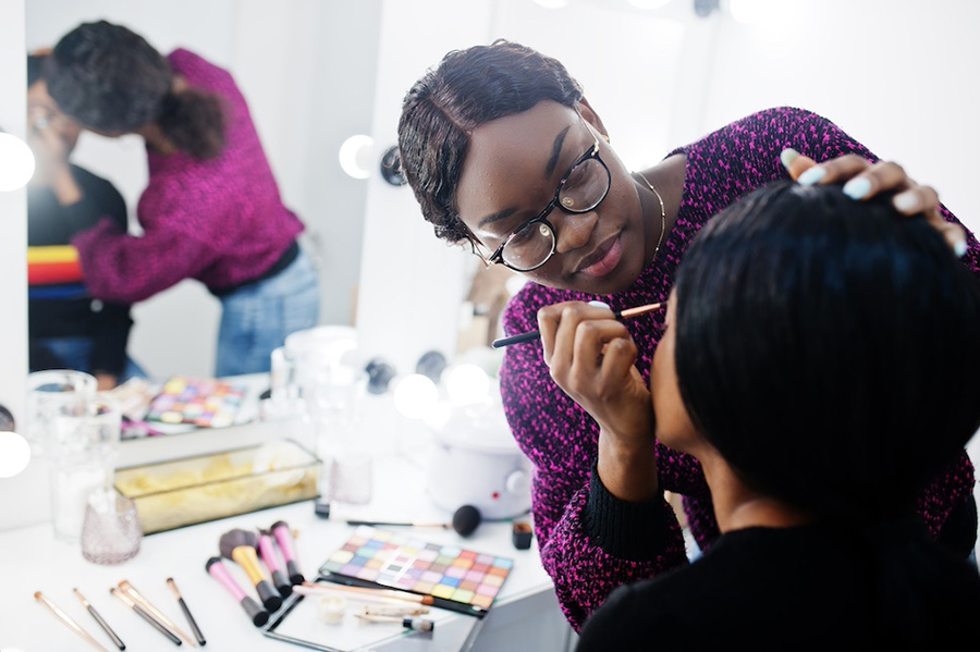 Beauty student applying makeup to another person's face in the beauty studio