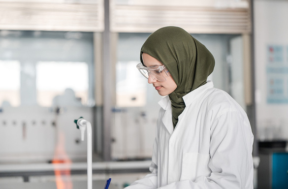 Student in Science lab at Harrogate College wearing safety goggles using a bunsen burner