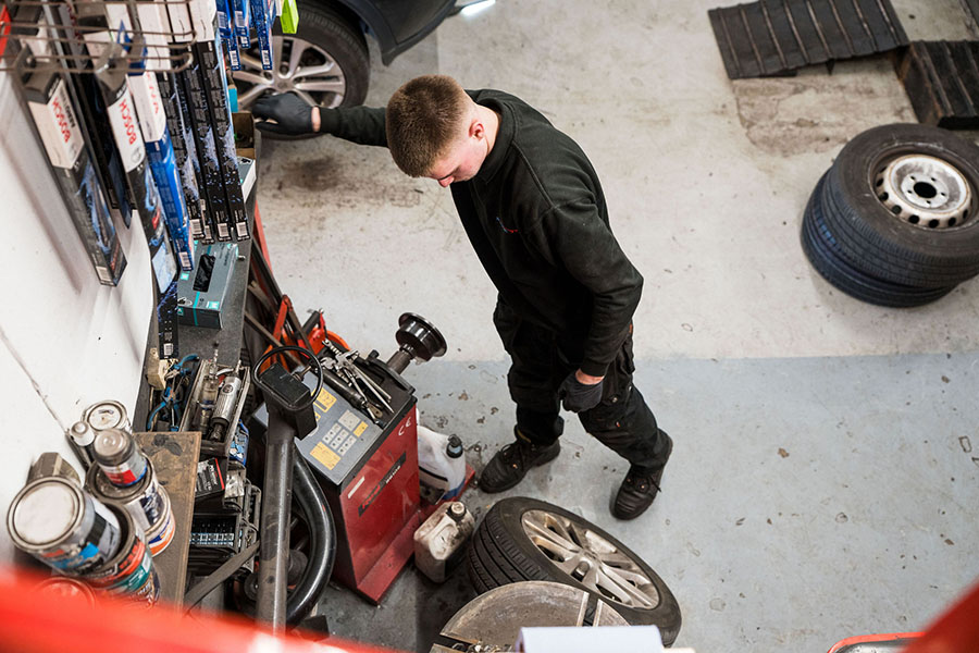 Motor vehicle student in the Harrogate College motor vehicle workshop looking at mechanical equipment