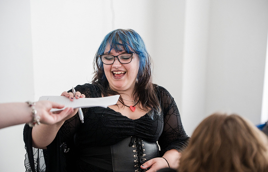 Image of a learner passing on notes smiling