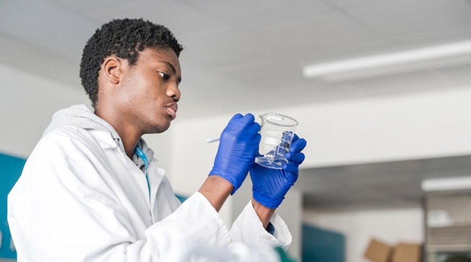 Student in the science lab at Harrogate College labelling the experiment glass cup with pen