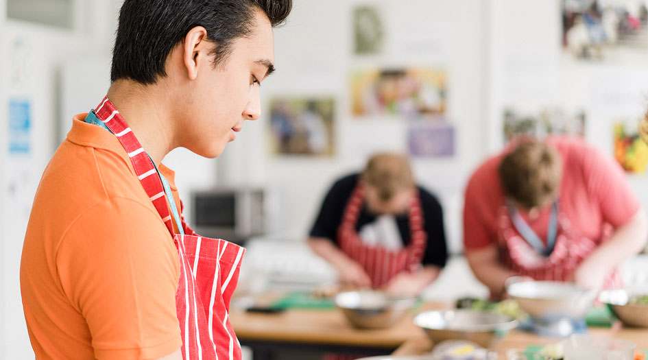 Foundation learning students wearing apron preparing food in the kitchen