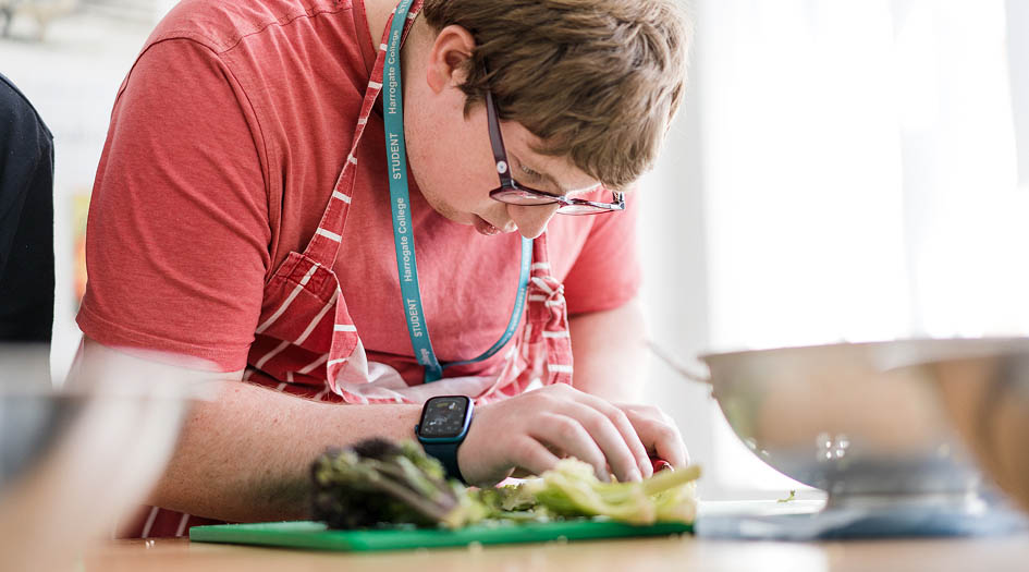 Foundation learning student wearing apron cutting vegetables in the kitchen