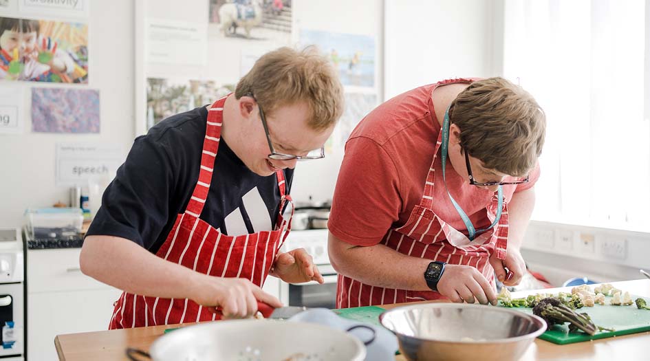 Foundation learning students wearing apron preparing food in the kitchen