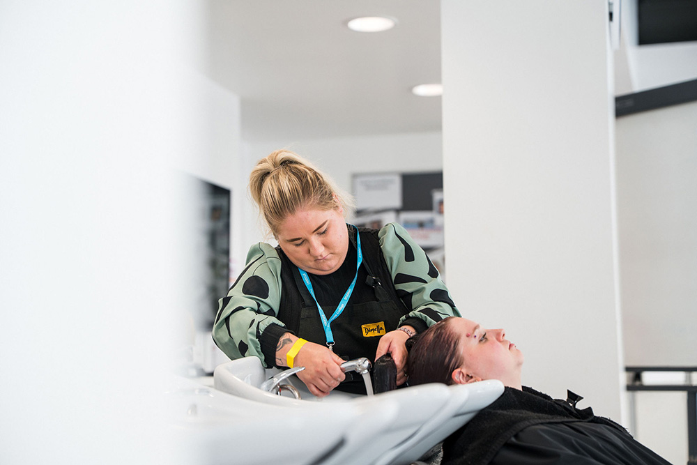 Student in the hairdressing salon washing someone's hair