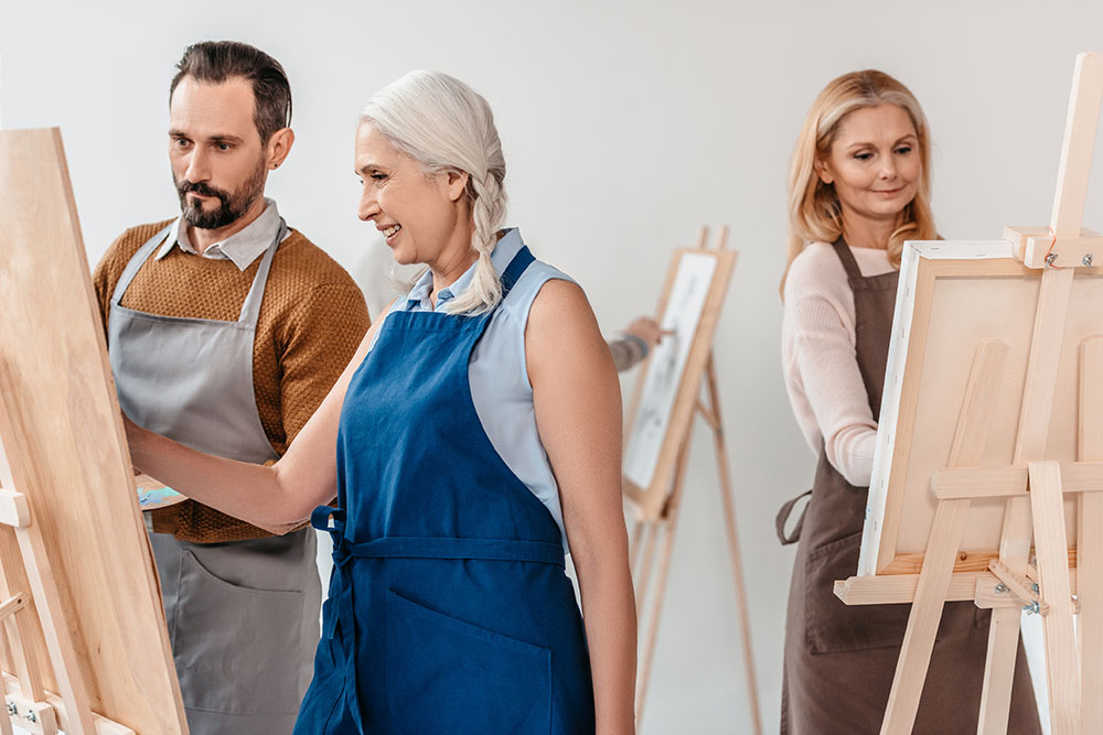 Adult students in a painting class painting on easels