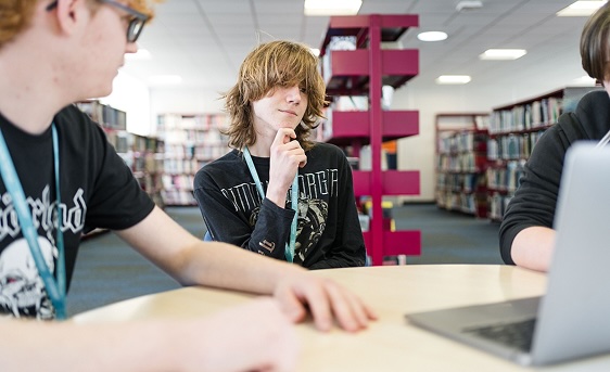 Three students sat in the library on their laptop studying