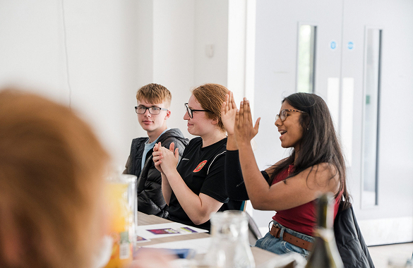 A group of students sat at a table clapping