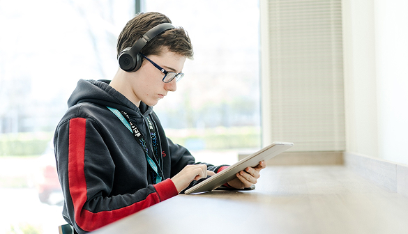 Student wearing headphones whilst reading a book