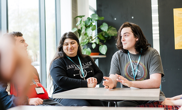 A group of students sitting in a social area within the college talking to one another