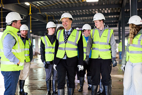 Staff and students wearing helmets and high vis smiling at the steel signing ceremony