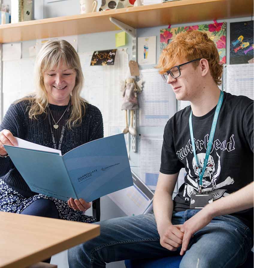 Apprenticeship mentor sat in the office looking through booklet talking with apprentice