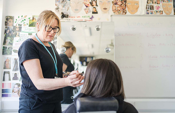 Adult beautician applying makeup to a face in the beauty salon at Harrogate College