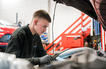 Student checking the engine bay of a car in the motor vehicle workshop