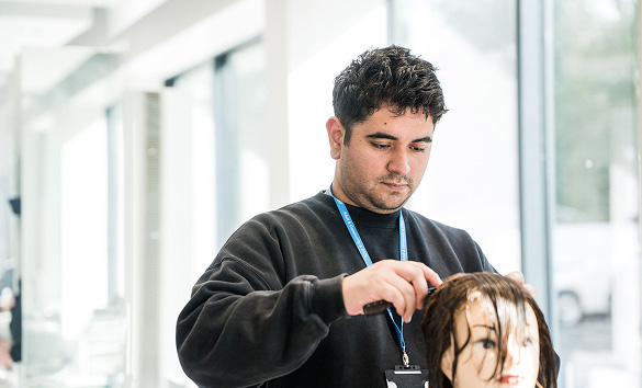 Adult student cutting hair on a mannequin in the hair salon at Harrogate College