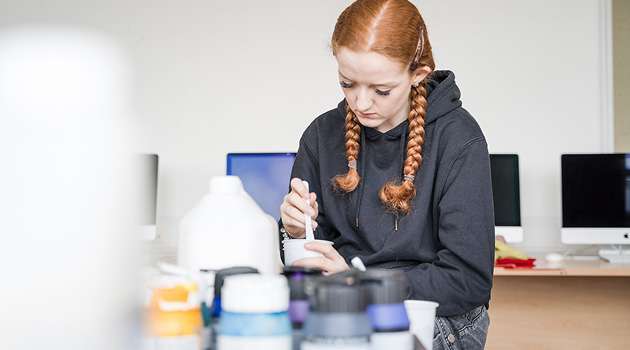 Creative Arts student sat mixing paint