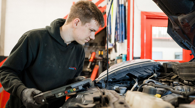 Student checking the engine bay of a car in the motor vehicle workshop