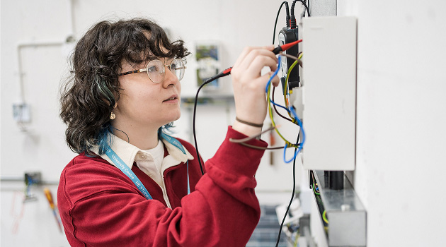 Student stood in workshop working on an electrical circuit board
