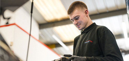 Person in workshop wearing a black top, looking down and smiling