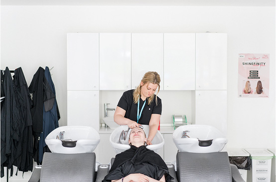 Harrogate College student washing a customer's hair in salon's training wash basins