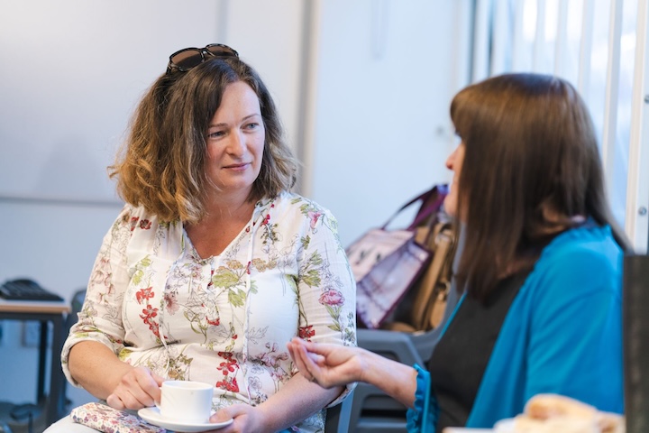 Two woman sat together looking at each other having a discussion