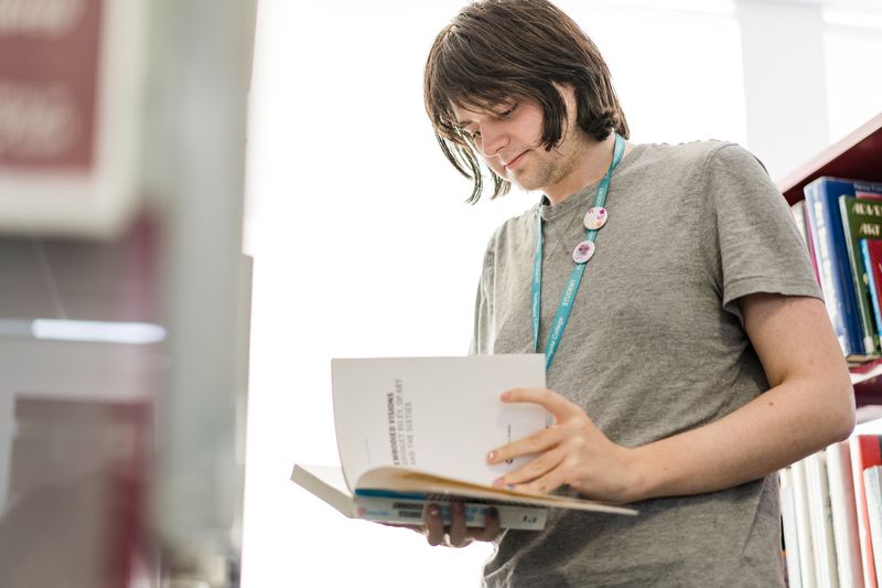 Adult student reading a book in the library
