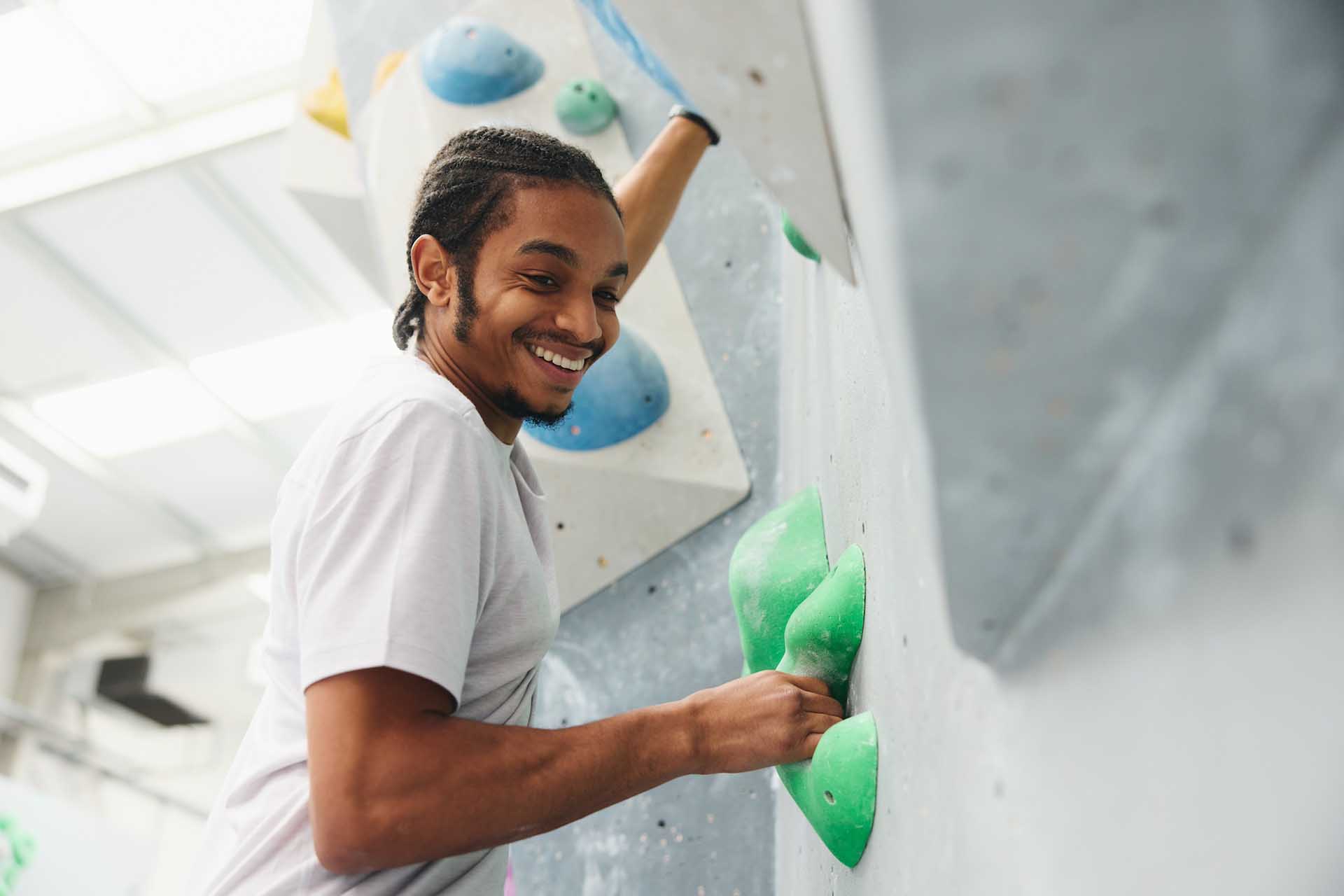 Close Up Of Smiling Man Enjoying Climbing Wall In Indoor Activity Centre