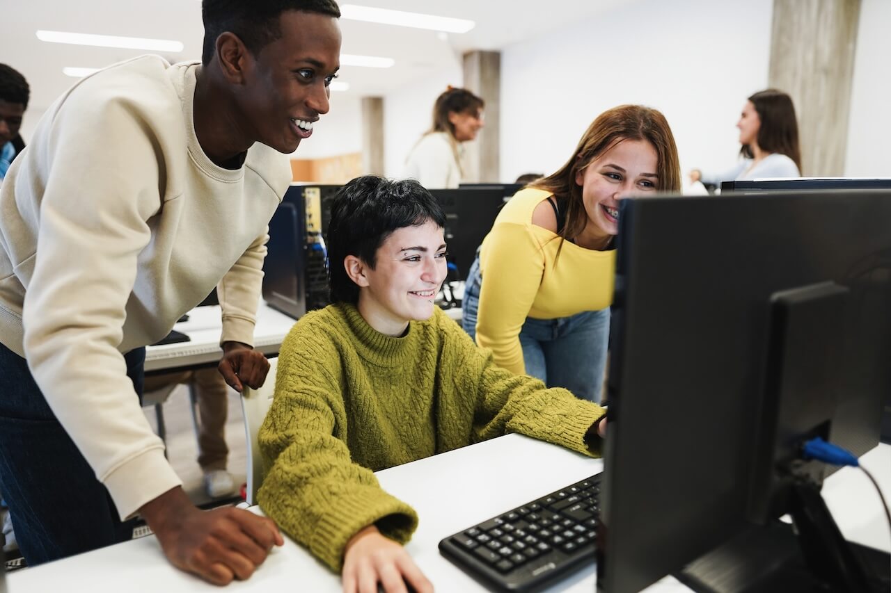 Three students around a desktop working